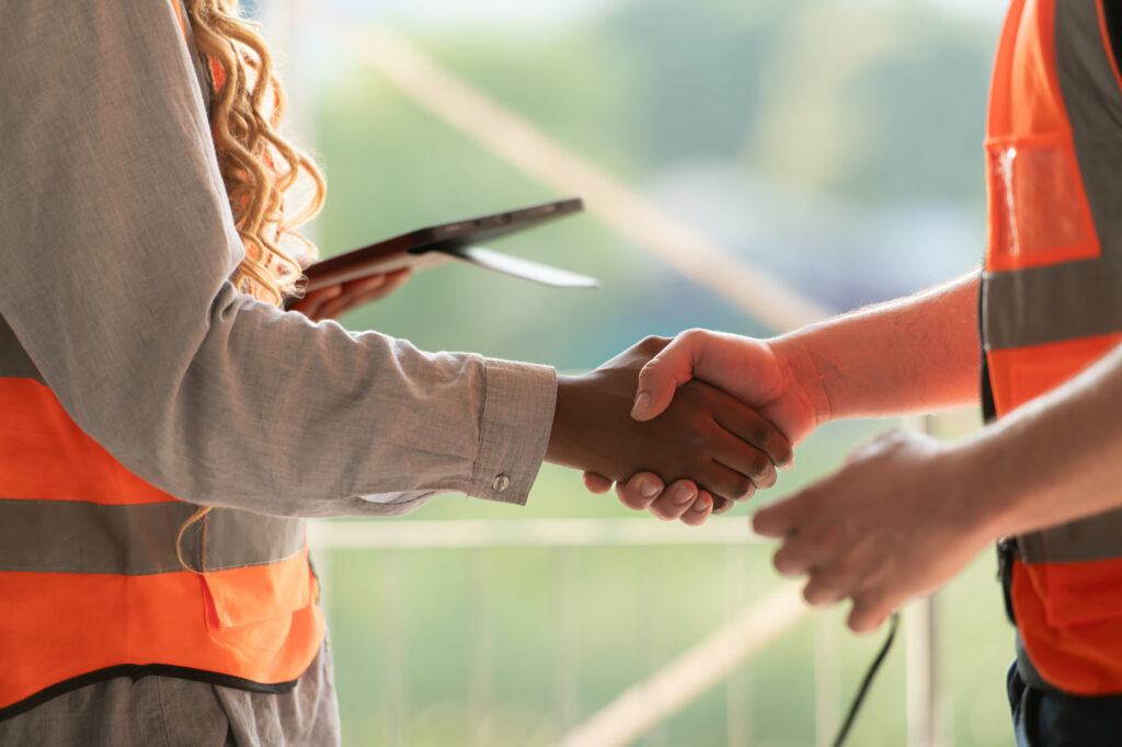 Architect and engineer discussing plans and shaking hands on a building project